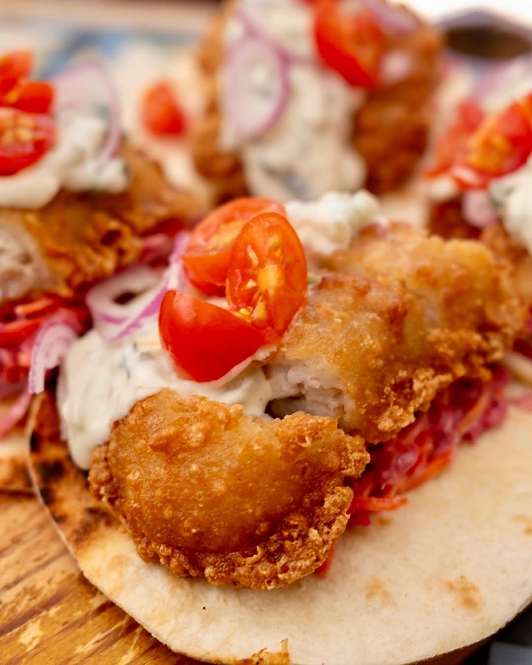 Taco com recheio panado, tomate cherry, cebola roxa e molho branco